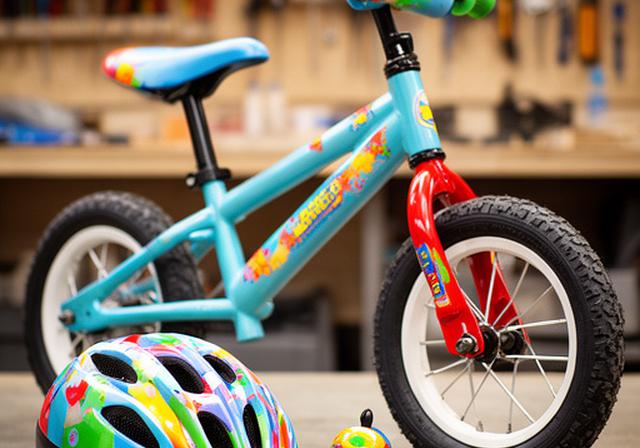 Bicicleta infantil colorida alinhada com capacete pequeno e campainha