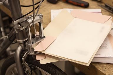 Fecho de bicicleta e documentos guardados numa bancada de oficina com luz suave
